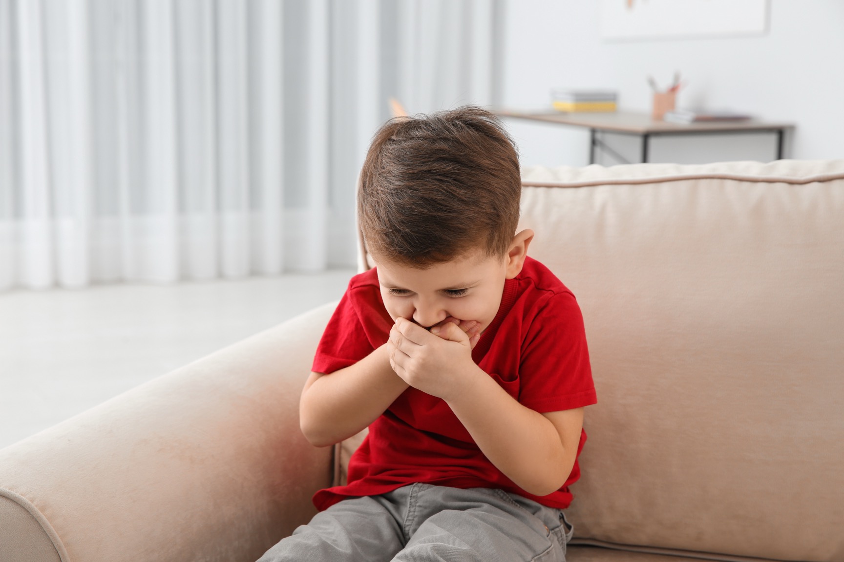 Niño pequeño que sufre náuseas en la sala de estar